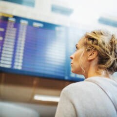 Frau guckt am Flughafen auf eine Anzeigetafel