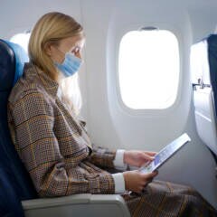 Frau im Flugzeug mit Maske